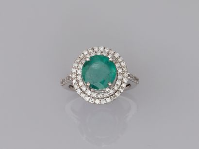 null 18k white gold ring set with a round emerald of about 4cts in a double surround...
