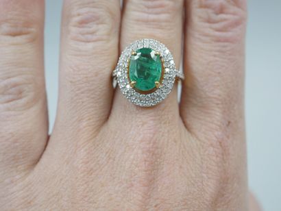 null 18k yellow gold ring set with an oval emerald of about 3 cts in a double border...