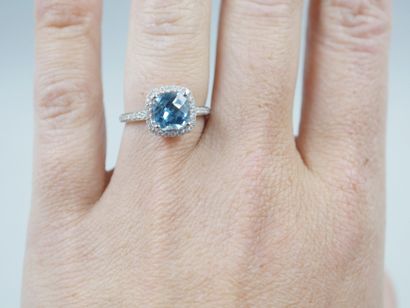 null 18k white gold ring set with a faceted cushion-cut blue topaz in a diamond setting....