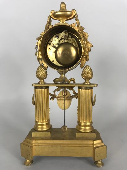  Pendule en bronze ciselé doré, le cadran inscrit dans une frise de lauriers et sommé...
