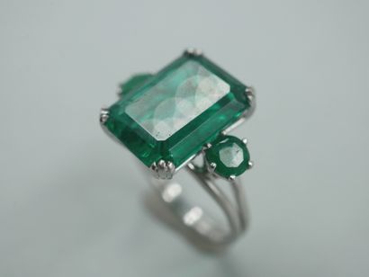 null 18k white gold ring set with an emerald-cut green stone and two green stones....