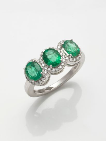 null Trilogy ring in 18k white gold set with three oval emeralds each in a diamond...