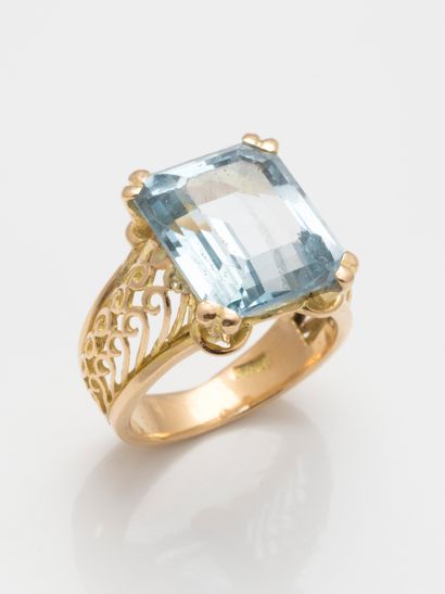 null 18k yellow gold cocktail ring set with an emerald cut aquamarine. The openwork...