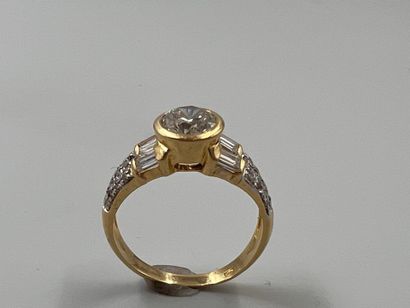 null 18k yellow gold ring set with a 1ct brilliant-cut solitaire diamond and baguette-cut...