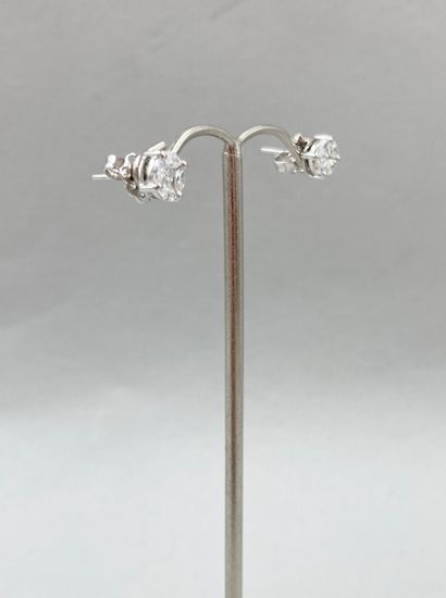 null Pair of round earrings in 18k white gold, each adorned with a princess cut diamond...