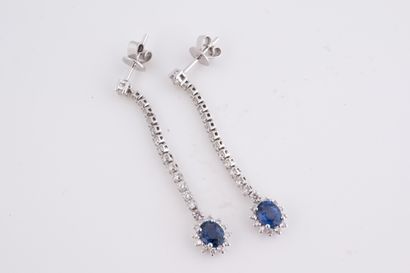 null Pair of 18k white gold earrings each set with an oval-cut sapphire surrounded...