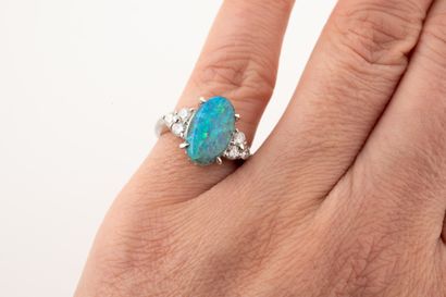 null Platinum ring set with an oval opal of about 3cts, surrounded by six brilliant-cut...