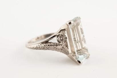 null 18k white gold ring set with an emerald-cut aquamarine flanked by two brilliant-cut...