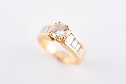 null 18k yellow gold ring set with a 1.10ct brilliant-cut diamond and a line of baguette-cut...