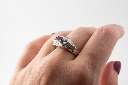 null 18k white gold ring set with an oval ruby in a geometrical setting of 2cts baguette-cut...