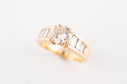 null 18k yellow gold ring set with a 1.10ct brilliant-cut diamond and a line of baguette-cut...