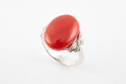 null 18k white gold ring set with a coral cabochon flanked by small bows adorned...