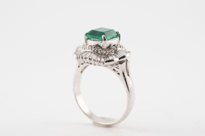null 18k white gold ring set with an emerald-cut emerald, approx. 2cts, in a scrolled...