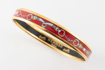 null HERMES Paris 
Bracelet en métal doré et émail à décor de mors sur fond rouge.
Signé....