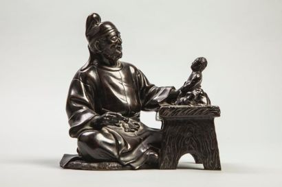 Arts d'Asie Lettré coiffé d'un bonnet, assis sculptant une figurine. Bronze. Japon....