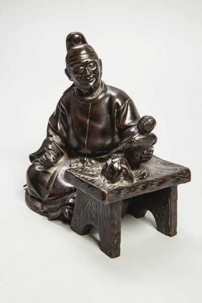 Arts d'Asie Lettré coiffé d'un bonnet, assis sculptant une figurine. Bronze. Japon....