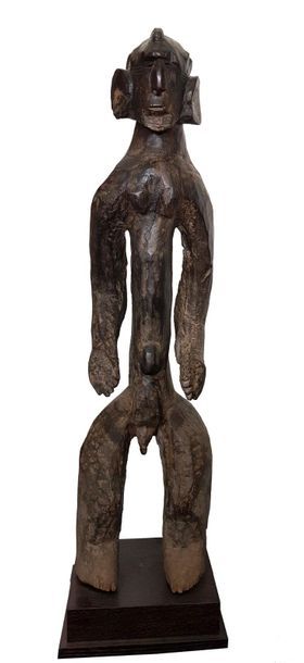 STATUE MUMUYE Standing with dangling arms, the scarified face with the protruding...