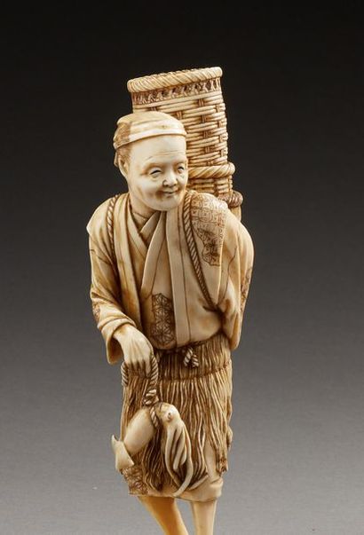 JAPON 
Bel okimono en ivoire sculpté représentant un pêcheur supportant des nasses...