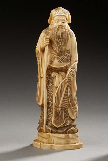 JAPON 
Okimono en ivoire sculpté représentant un mandarin debout sur un rocher tenant...