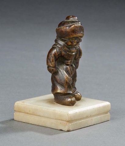 null PETIT SUJET en bronze figurant un enfant vêtu d'un bonnet marchant sur un socle...