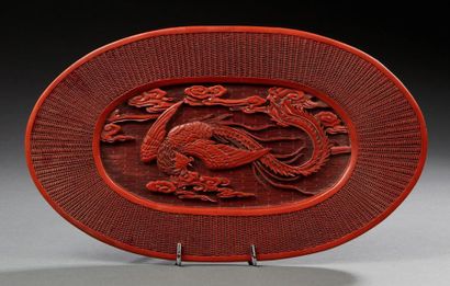 CHINE Plat ovale en bois laqué rouge à décor central d'un paon en relief.
Dim : 16...
