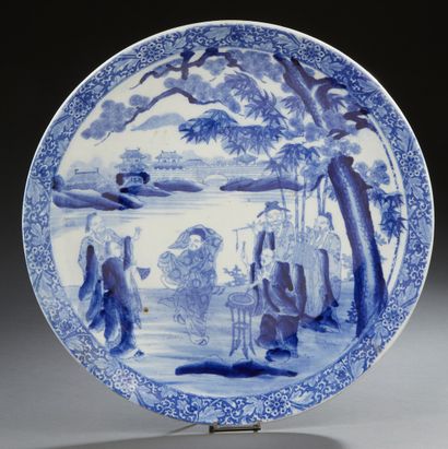 JAPON Grand plat en porcelaine décoré en bleu sous couverte de personnages dans un...