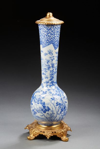 JAPON Vase à long col en porcelaine décoré en bleu sous couverte de fleurs et feuillages....