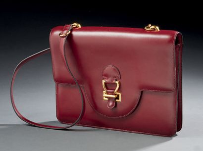 HERMES Sac à main en cuir bordeaux de forme rectangulaire, il ouvre par un système...