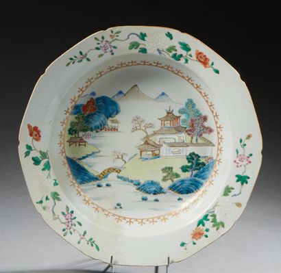 CHINE Plat creux en porcelaine décoré en émaux de la famille rose d'un paysage fluvial...