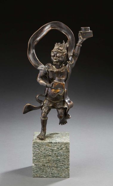 JAPON Statuette en bronze à patine brune figurant un guerrier tenant deux lumières....