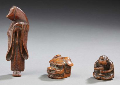 JAPON Trois netsuké en bois sculpté; l'un à décor de tête de lion bouddhique, les...