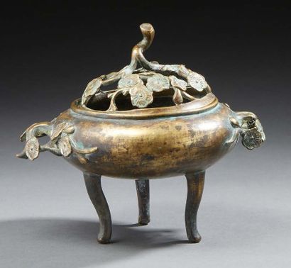 CHINE A circular bronze perfume burner with a brown and green patina resting on three...