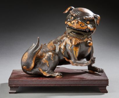 CHINE Figurine en bronze à patine brune rehaussée de dorures, représentant un lion...