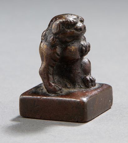 CHINE Petit sceau en bronze à patine brune représentant un lion bouddhique portant...