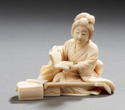 JAPON A carved ivory okimono representing a young musician sitting and opening a...
