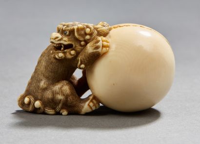 JAPON Beau netsuke en ivoire sculpté représentant un chien de fô accroche à une sphère,...