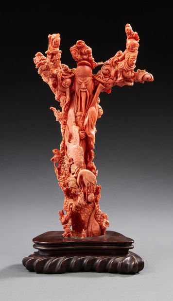 CHINE Branche de corail orange sculptée représentant un immortel appuyé contre un...