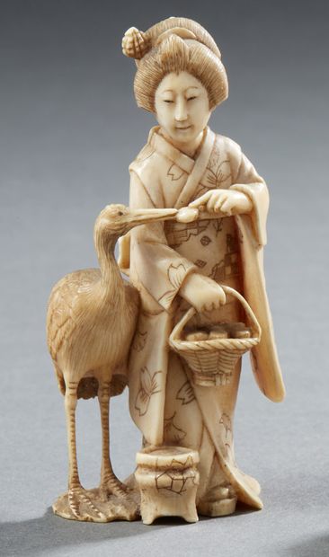 JAPON Petite okimono en ivoire sculpté représentant une bijin (beauté) vêtue d'un...
