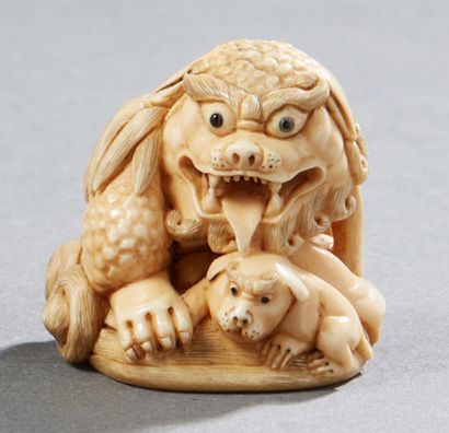 JAPON Netsuke en ivoire sculpté représentant un lion bouddhique assis sur un tertre...