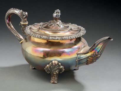 null A silver teapot, standing on three scrolled feet with leafy attachments. The...