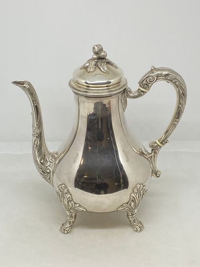 null A silver teapot resting on four scrolled feet, the frétel formed of a bunch...