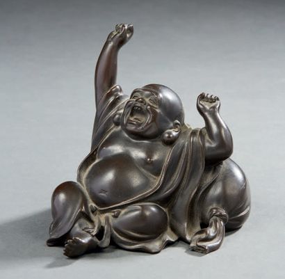 JAPON Figurine en bronze à patine brune représentant un bouddha baillant, assis contre...