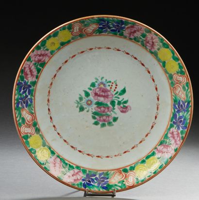 CHINE, XIXe siècle Plat en porcelaine à décor polychrome de fleurs au centre et en...