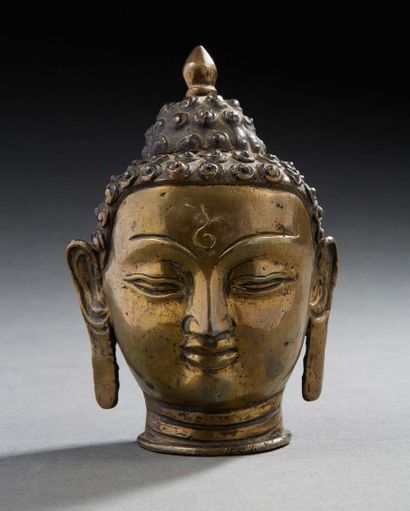 TIBET, XIXe siècle Petite tête de bouddha en bronze, les yeux miclos esquissant un...