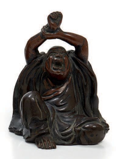 JAPON Figurine en bronze à patine brune et rouge figurant un homme assis se tenant...