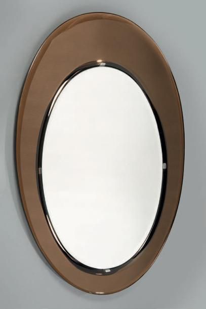 *FONTANA ARTE (XXe) 
Miroir ovoïde à encadrement en verre teinté brun biseauté en...