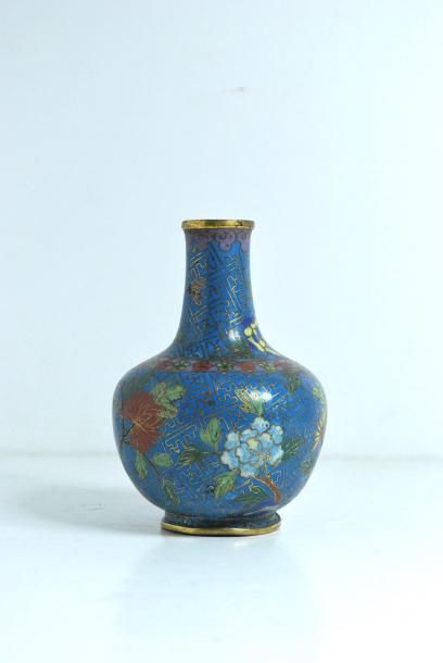 null Chine. Petit vase soliflore en émail cloisonné au fond bleu à motif floral.
(accidents)...