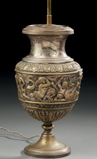 null Vase urne monté en lampe en métal repoussé argenté à décor frise d'après l'antique.
Fin...