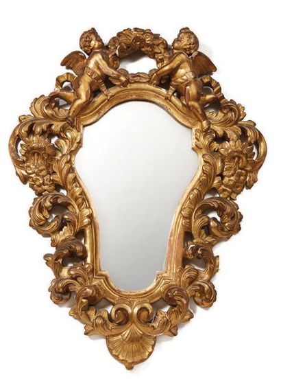 null Bevelled mirror in a carved and gilded wooden frame; with the damping of angels...