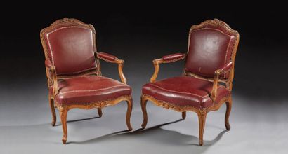 null Pair of flat-backed armchairs in molded walnut carved with stylized foliage...